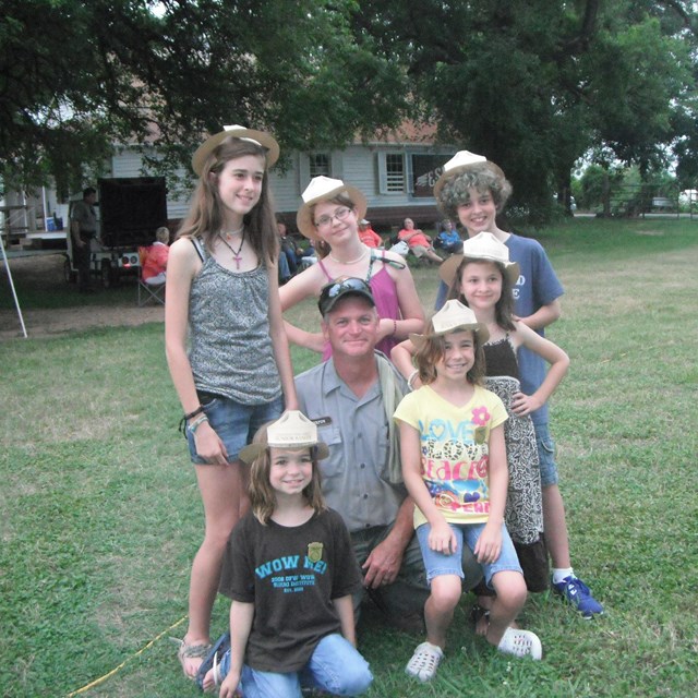 Ranger with six children, wearing Jr. Ranger hats.