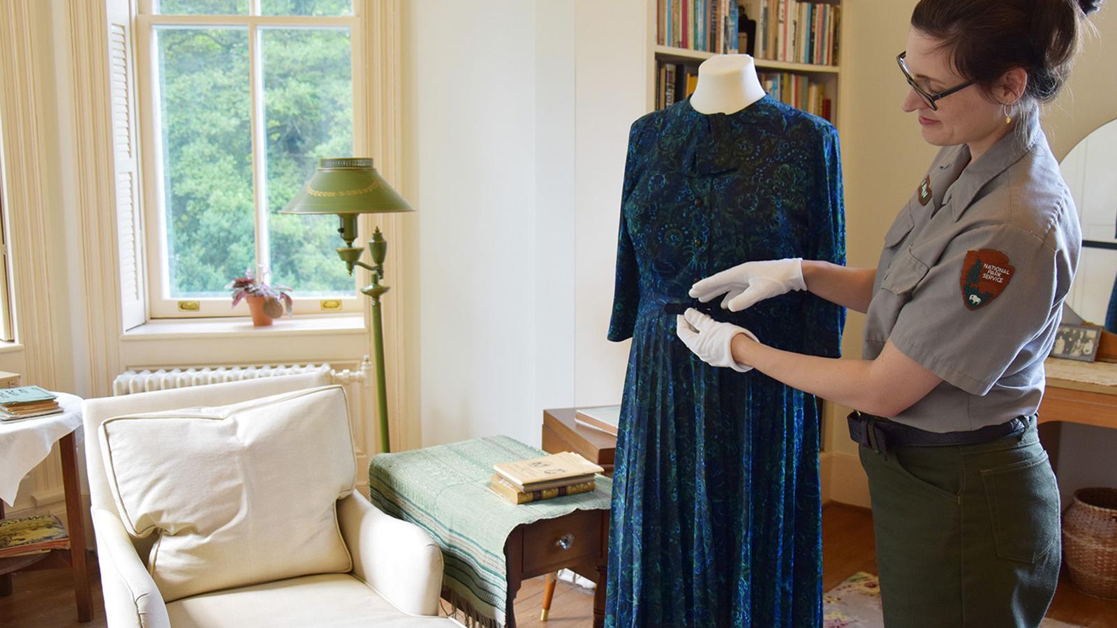 Image of museum curator inside the Sandburg Home caring for a textile object