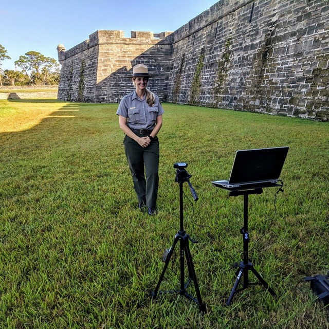 Ranger in moat with fort in background and laptop/camera filming her. 