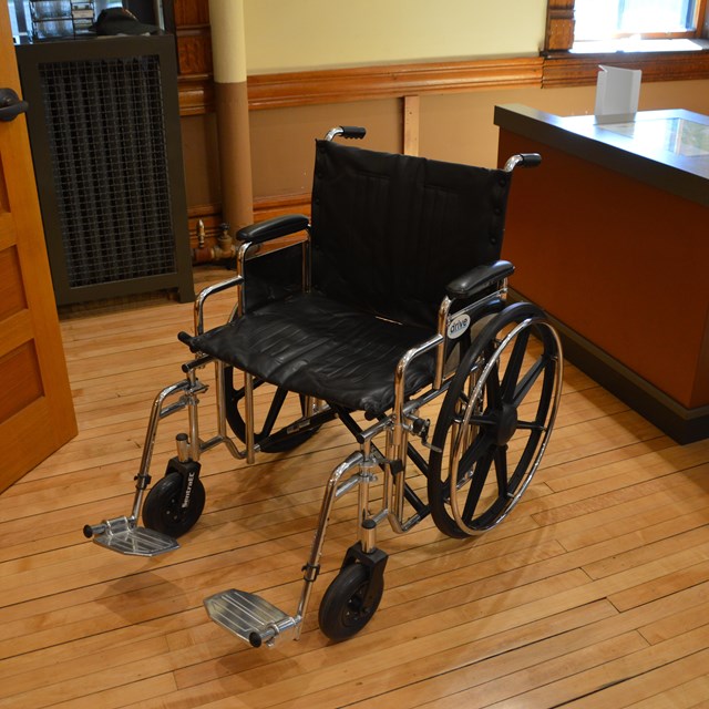 An empty wheelchair next to a desk.