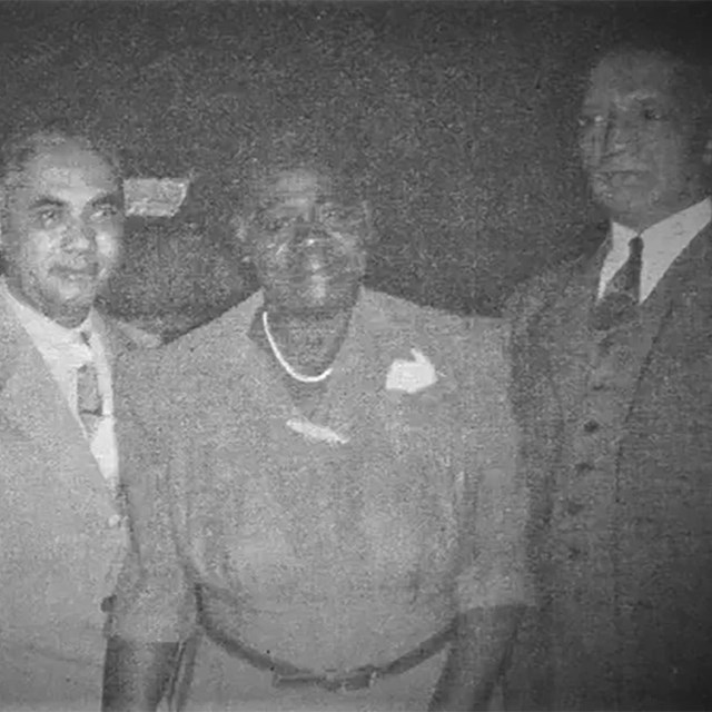 Formal photo of four Black scholars, three men flanking one woman.