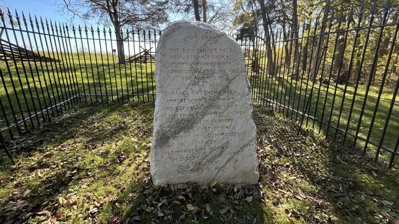 Marble monument inside an iron fence. 