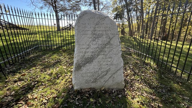 Marble monument inside an iron fence. 