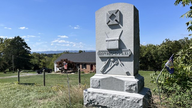 A large stone monument etched with crossed rifles and a knapsack. 