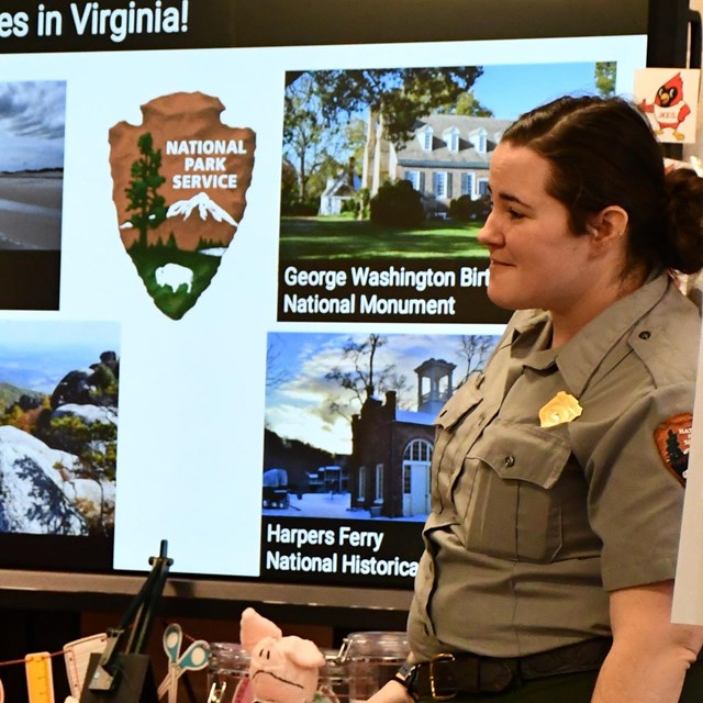 A park ranger listens to students while presenting in a school library.