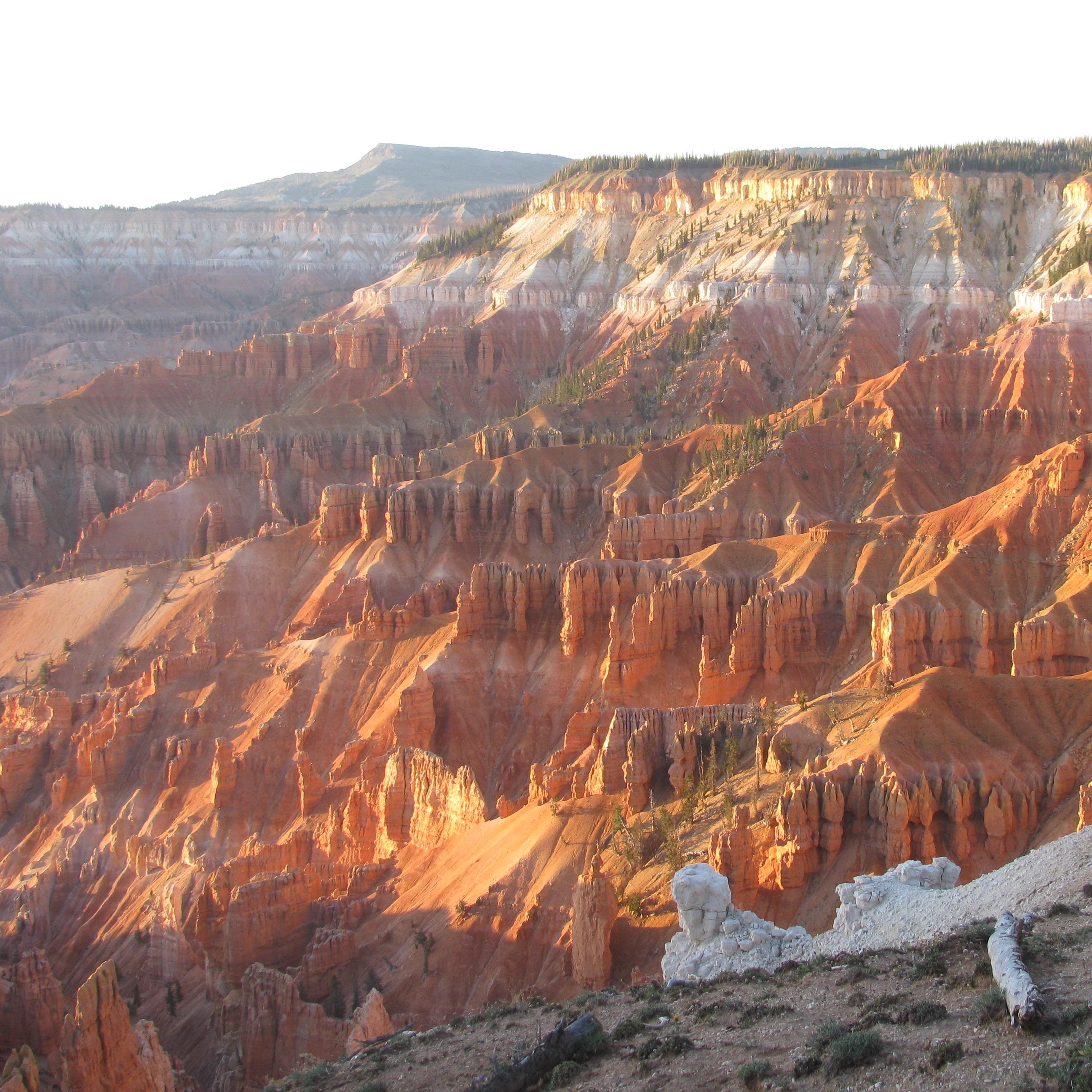 Massive geologic formation featuring orange, red, pink, and purple rocks.