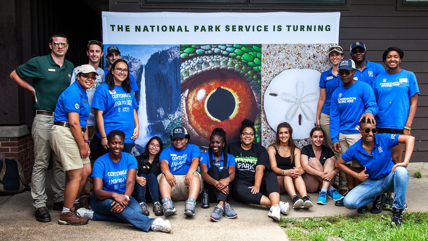 Young adults gathered around in front of a centennial banner.