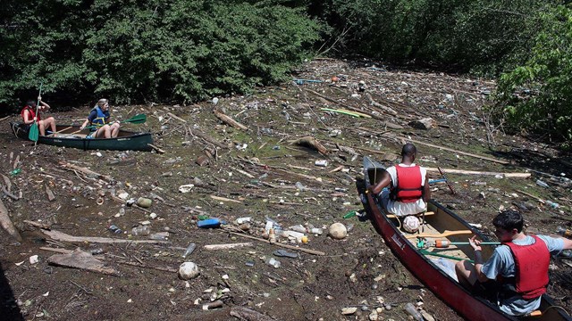 Two canoes surrounded by trash in the river during one of many river cleanups.