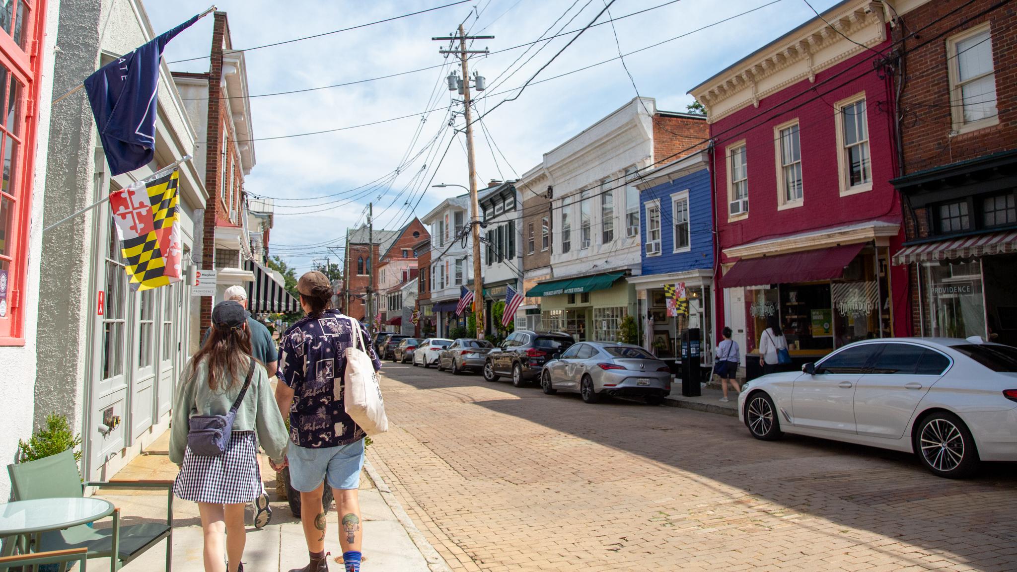 Two people walk along the sidewalk of a historic street in the mid-Atlantic.