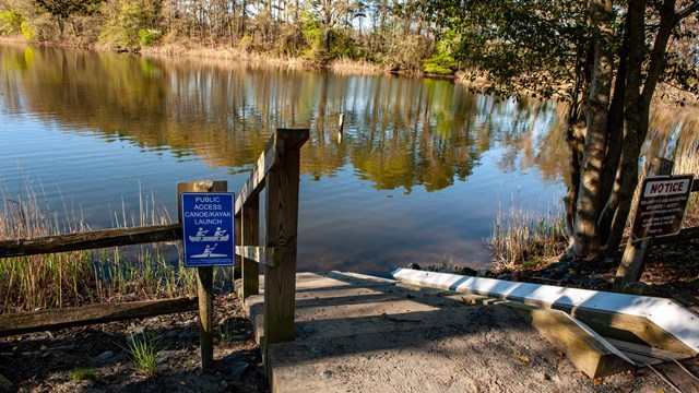 A kayak launch runs next to a set of stairs leading to water.