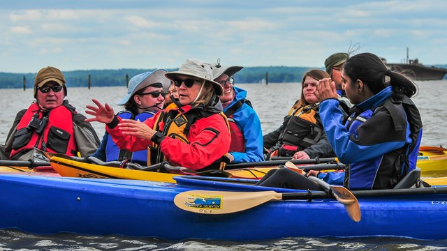 A group of kayakers gather to talk while on the water.