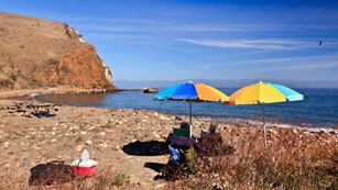 Visitors sitting on beach with umbrellas. ©Tim Hauf, timhaufphotography.com