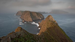 Three islets surrounded by blue water and fog. ©Tim Hauf, timhaufphotography.com