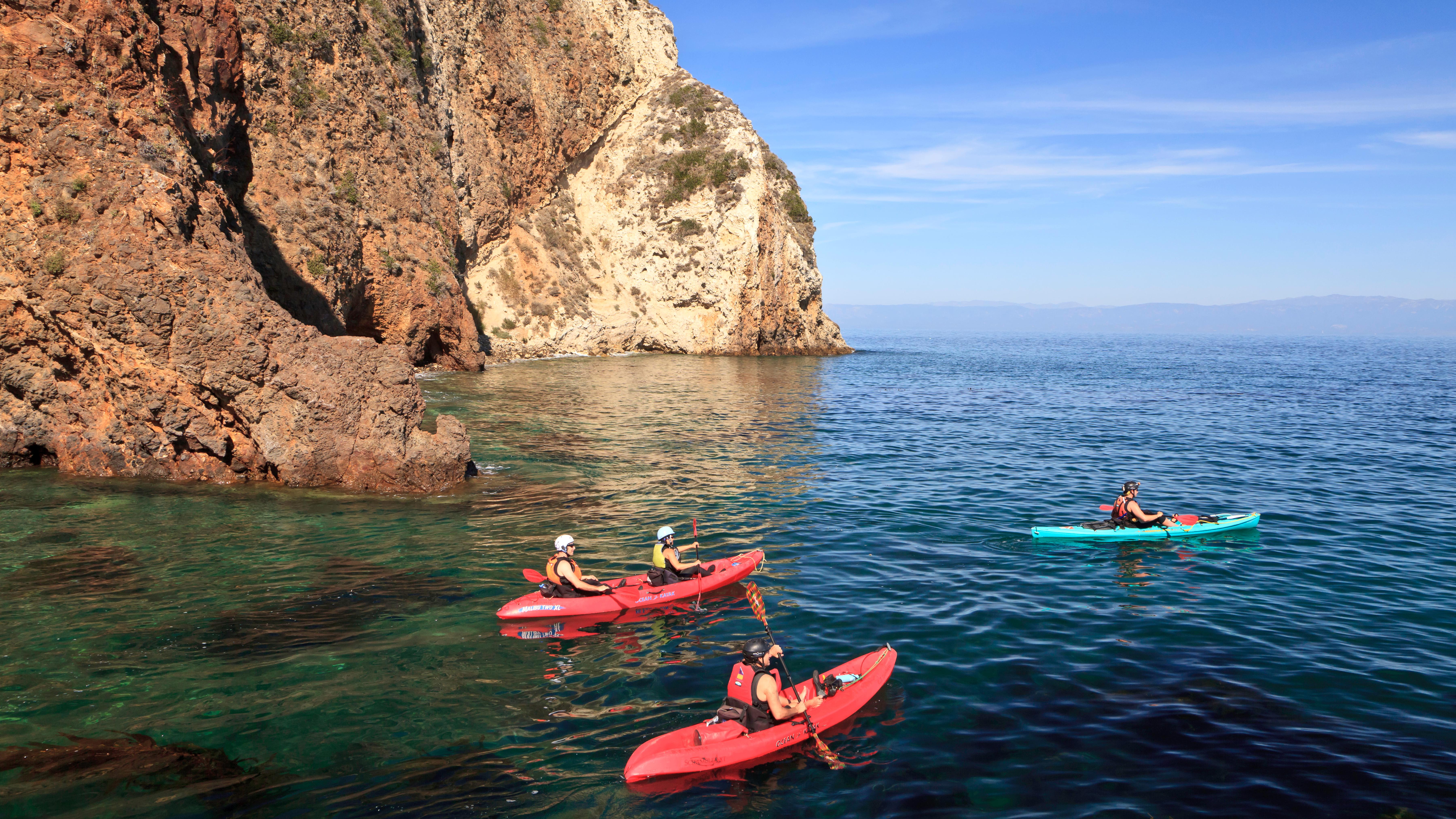 Kayakers in blue water next to steep cliff. &copy;Tim Hauf, timhaufphotography.com