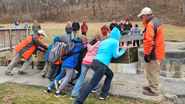 Student pushing to open a lock on the canal supervised by Canal Classroom Corps teachers.