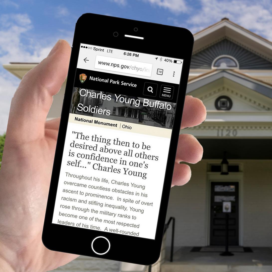 A hand holding a smart phone with browser showing the park's website being displayed