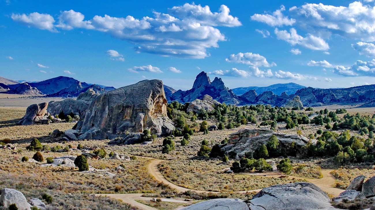 A scenic vista of rocks formations and trails. A cloudy sky is seen. 