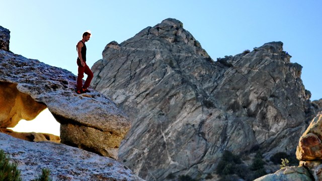 A person walks along the top of a granite formation.