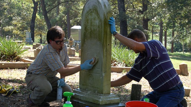 two men scrub and old gravestone