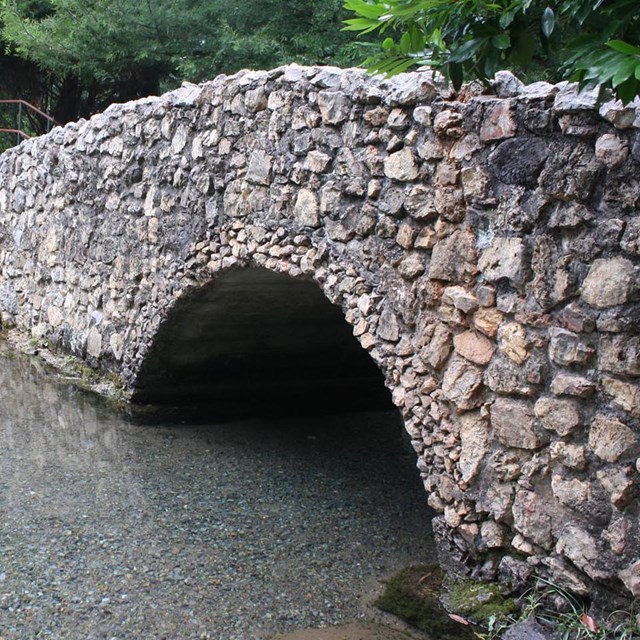 a stone bridge crosses a small creek