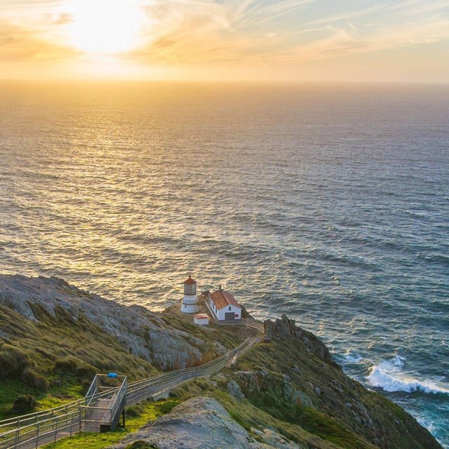 A hill with a lighthouse overlooking an ocean