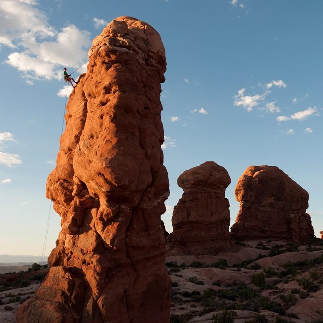 Photo of a man rappelling off a sandstone spire, Arches National Park