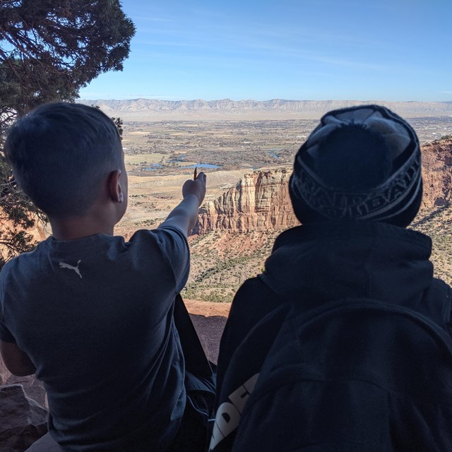 Students point to a canyon below.