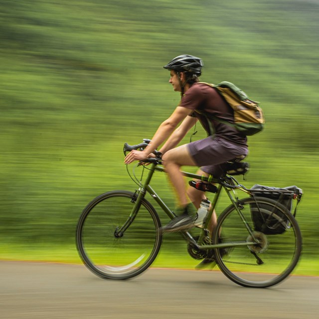 a person with a helmet riding a bicycle with motion blur in the background