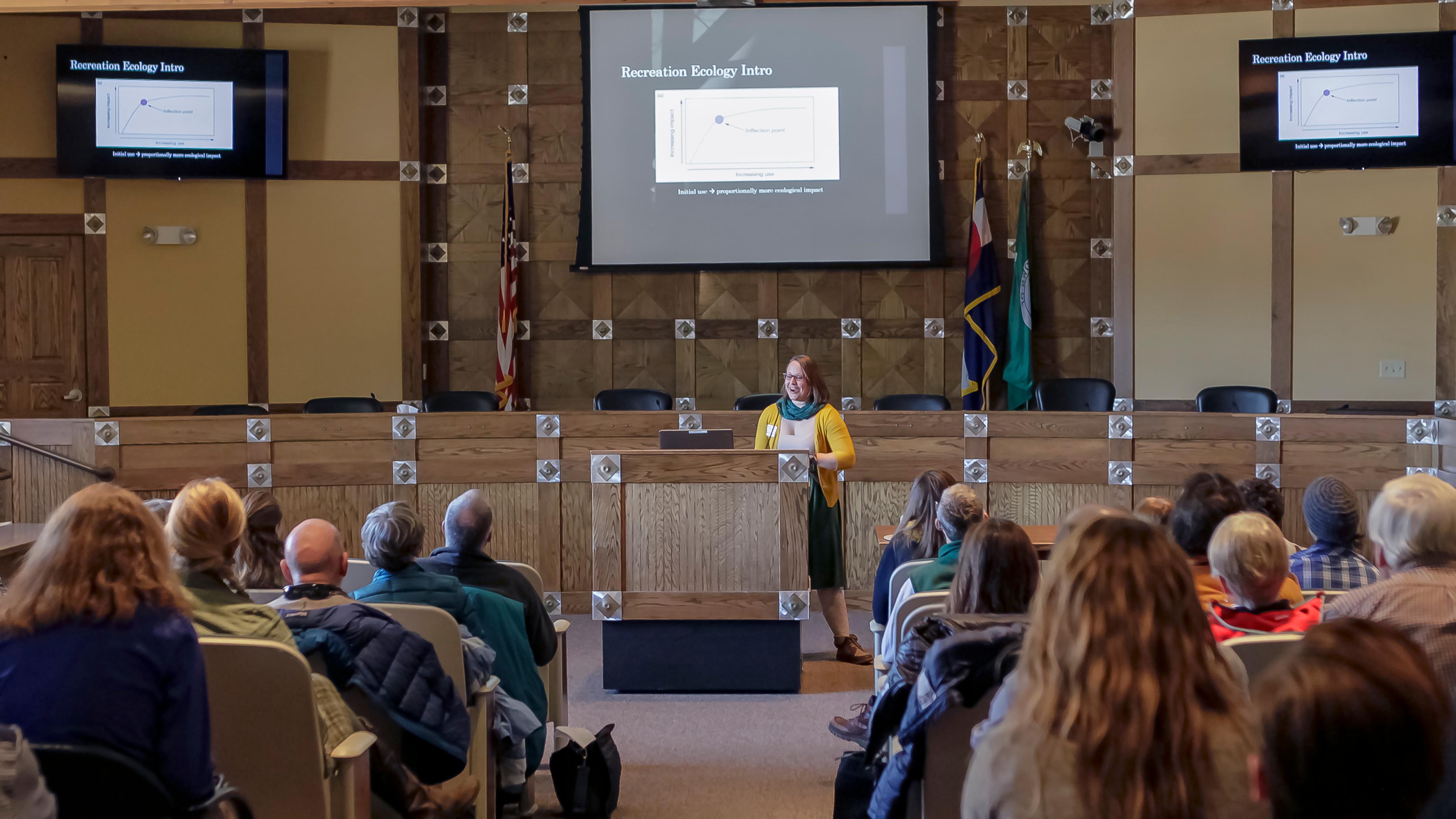 Researcher presents at a podium to an auditorium of people.