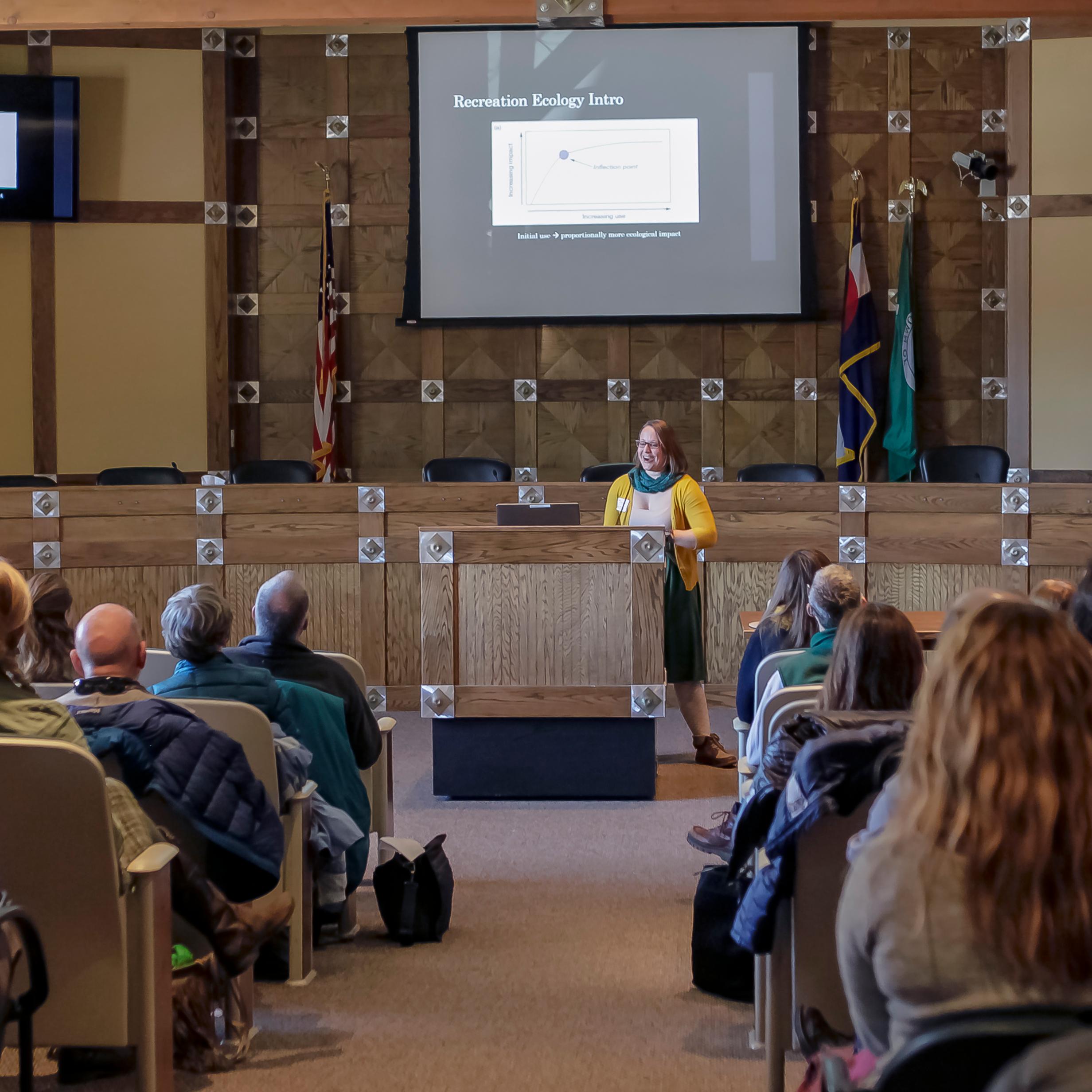 Researcher presents at a podium to an auditorium of people.