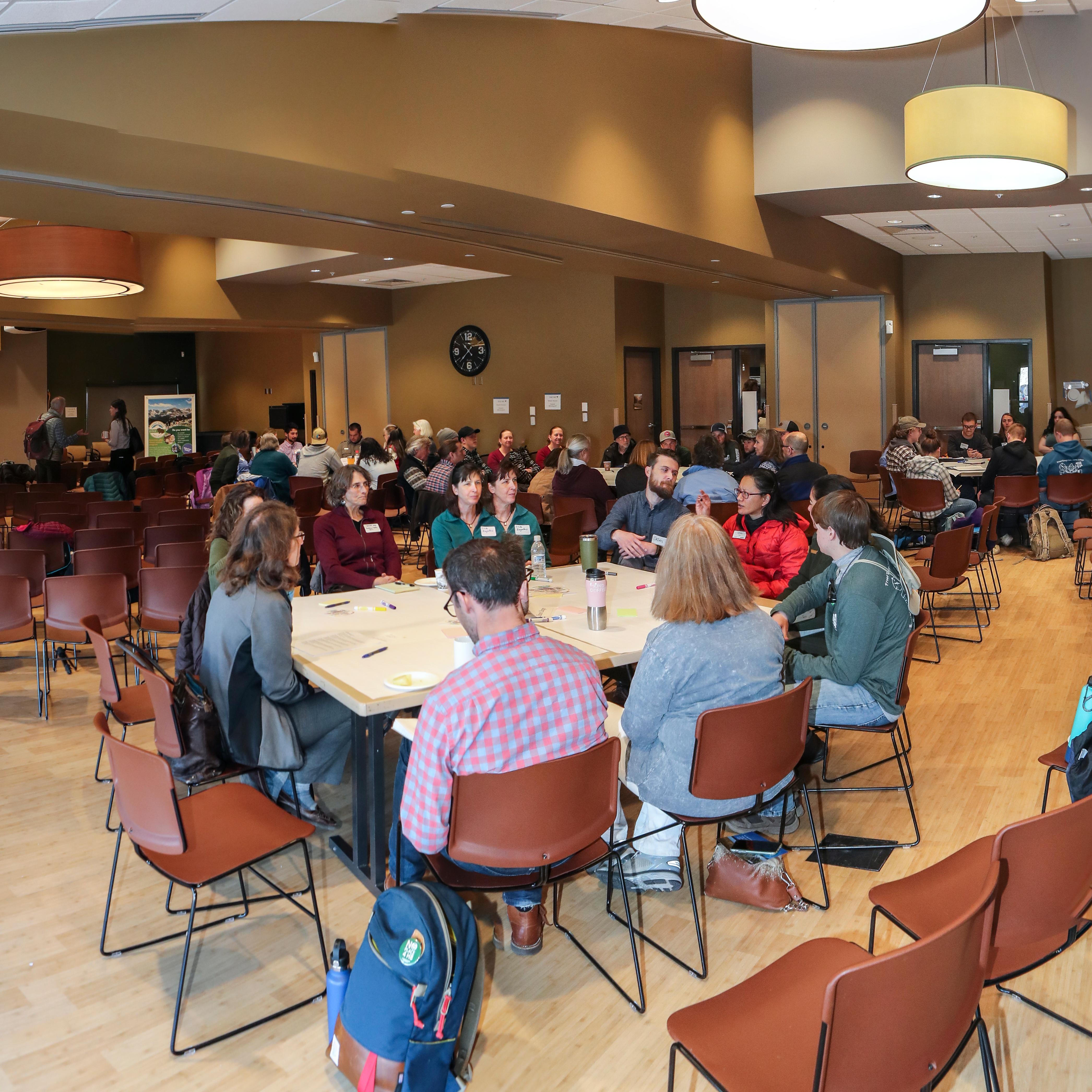 A room full of people at tables engaged in conversation. 