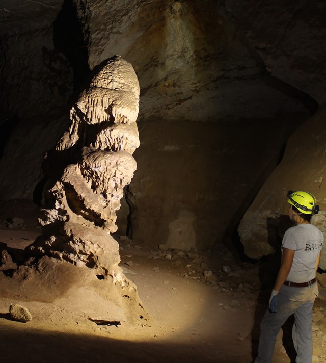 A cave explorer looks at a stalagmite 