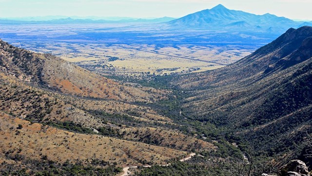 A view of a wide canyon with a dirt road 