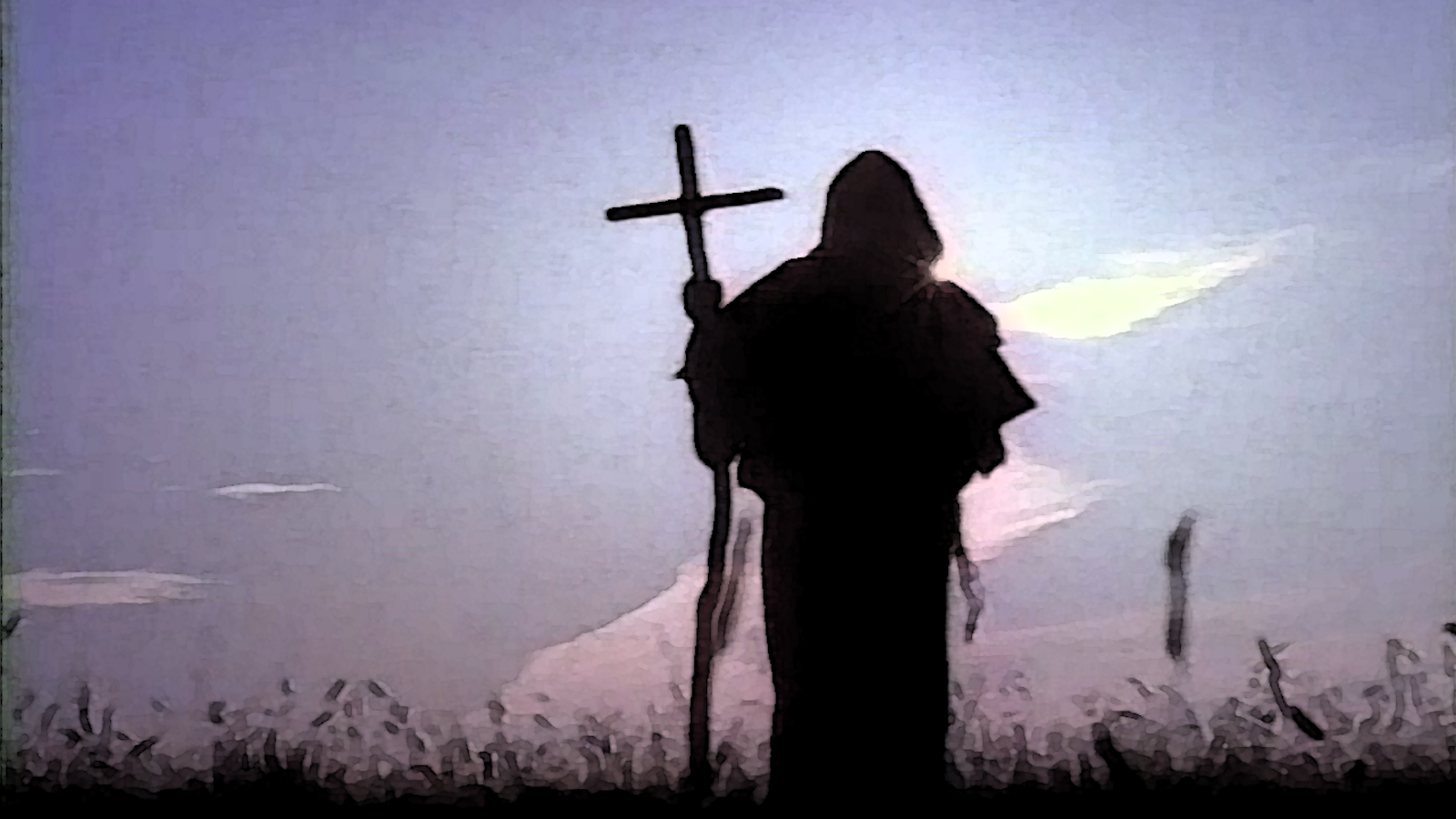 A man in hooded robe with cross lit in silhouette 