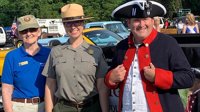 Three staff members and volunteers pose for a photograph in front of a truck. 