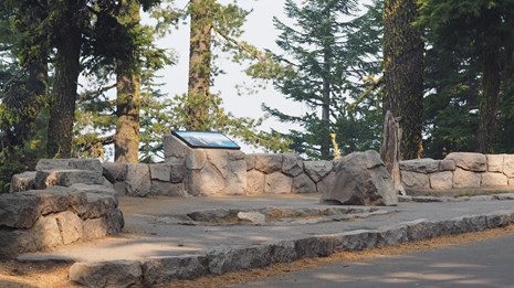 An information exhibit is set in a circular stone wall overlooking Crater Lake.