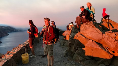 People  at Watchman peak overlooking the lake, faces aglow from the setting sun. sun