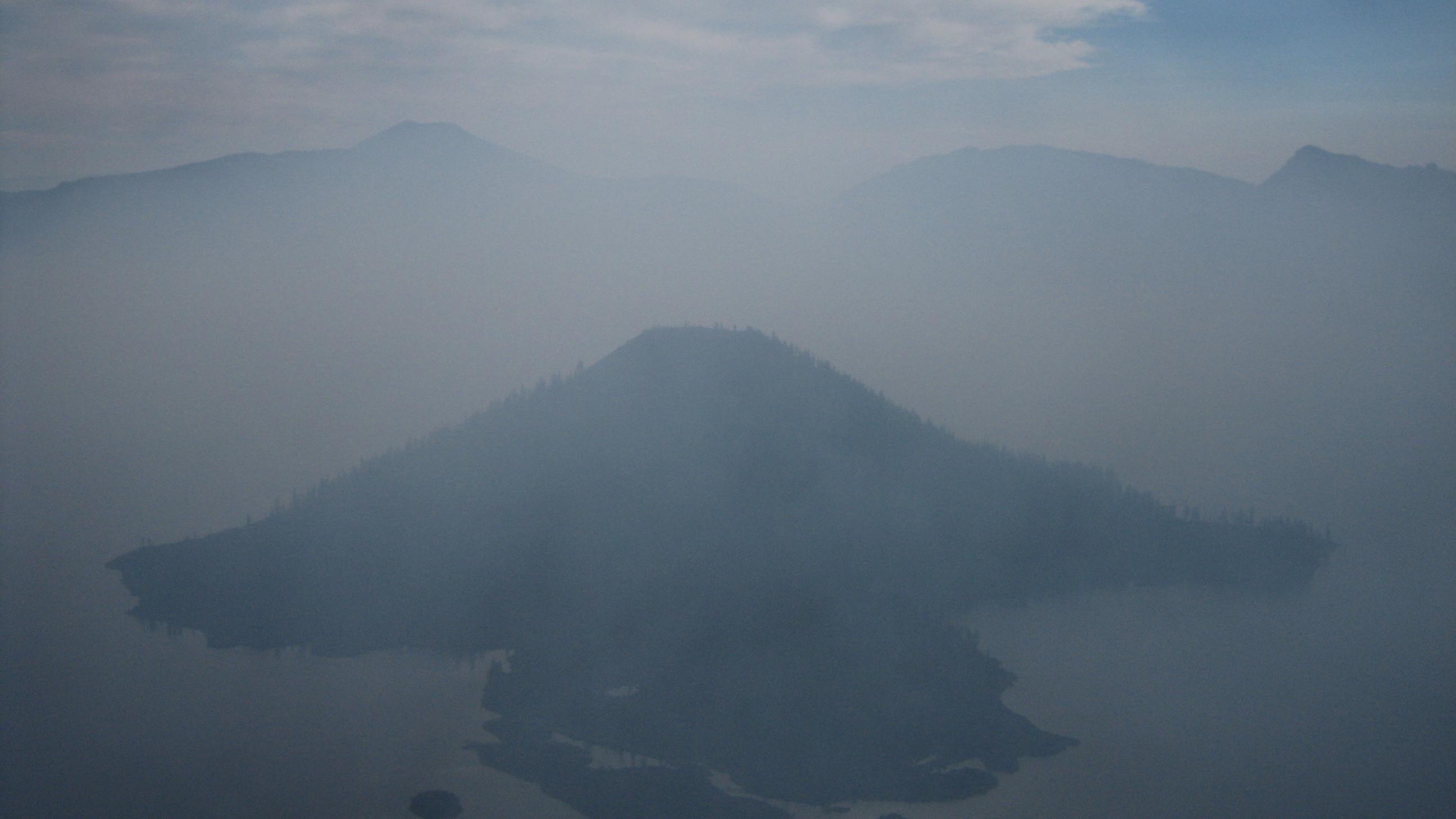 The Crater Lake Caldera is filled with smoke obscuring Wizard Island. 