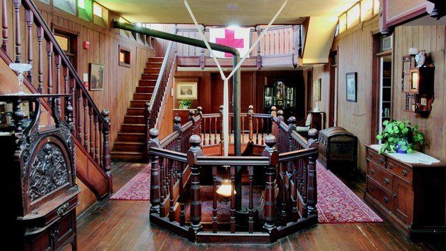 Interior of a historic home that includes a red cross flag and internal balcony