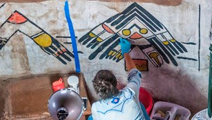 Conservationist working on Native American artwork on a wall