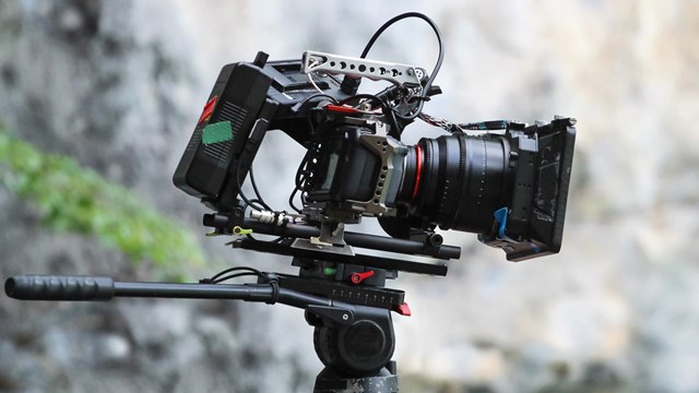 A video recorder in view with a rocky mountain face in the back.