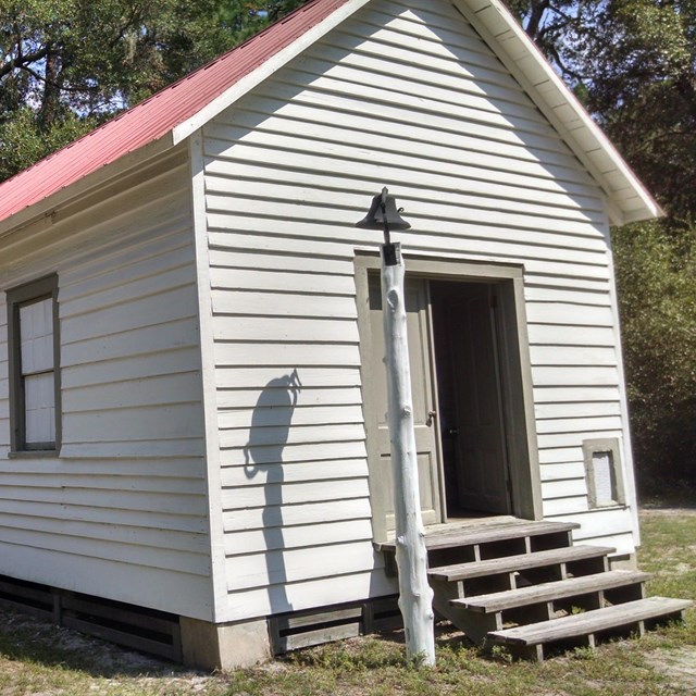 One room, white church with red roof surrounded by pine trees