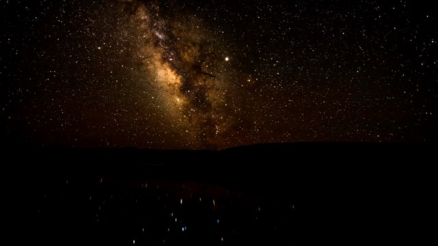 Image of the Milky Way and stars reflected over a body of water