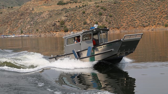 A metal boat leaving a wake on a reservoir