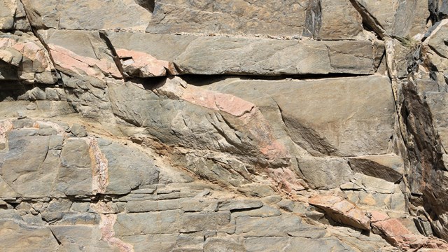 A light pink rock intrusion diagonally across a larger brown rock