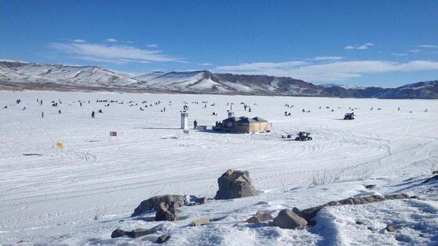 Multiple people out on ice during an ice fishing tournament.