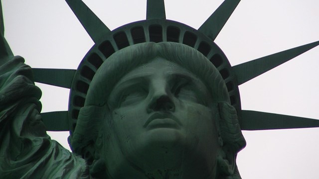 The head, crown, and right shoulder of the Statue of Liberty fill the frame.