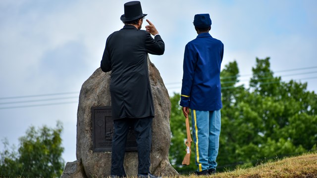 an Abraham Lincoln reenactor and young visitor talking; facing away from the camera