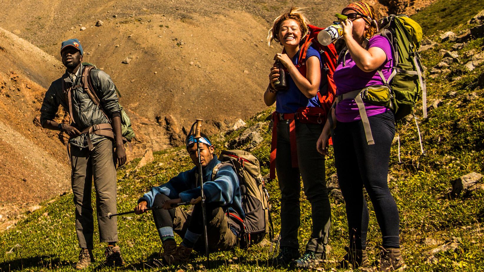 Three people pausing on a hike on a hillside