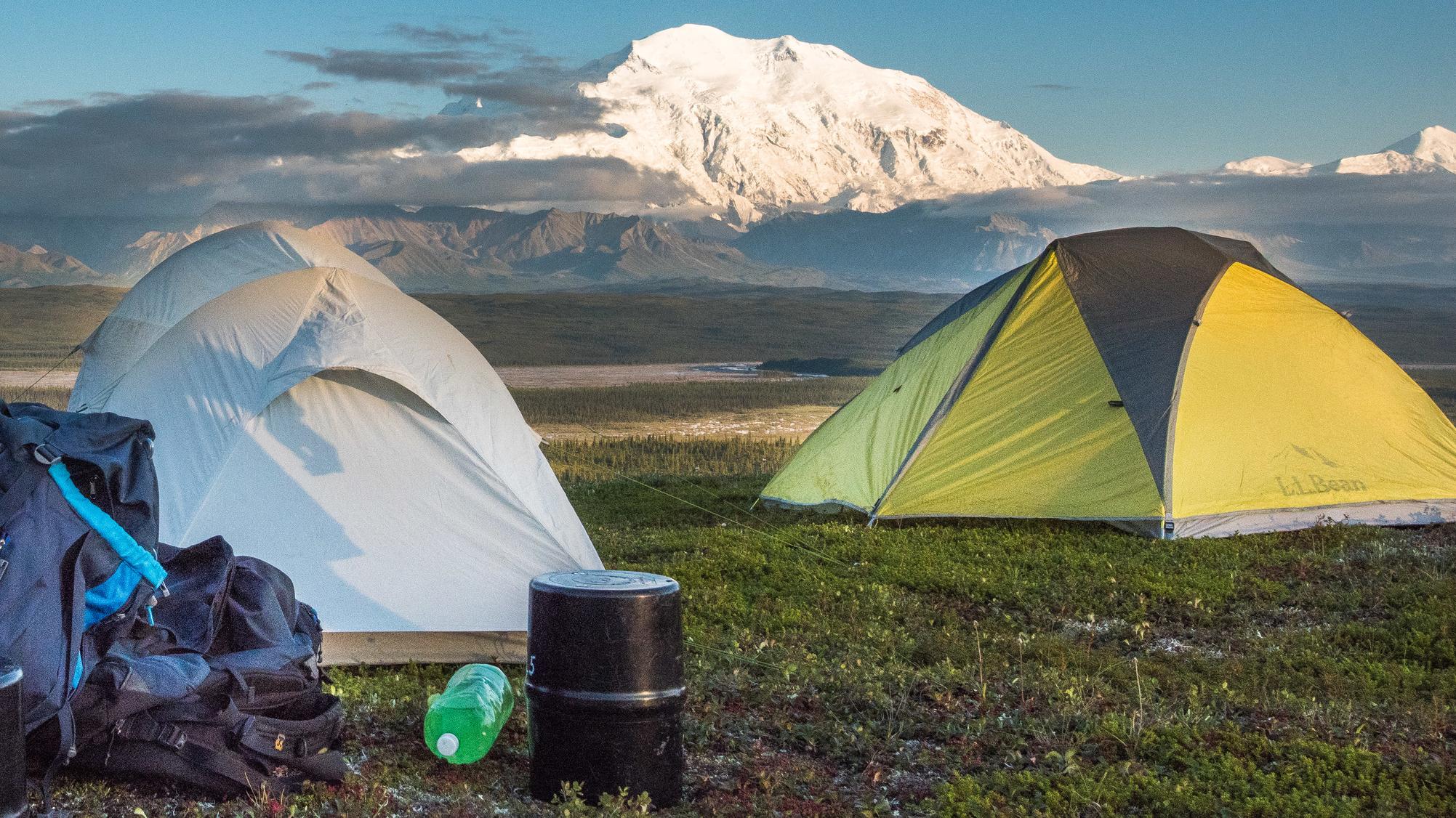 Two tents and gear on a hillside